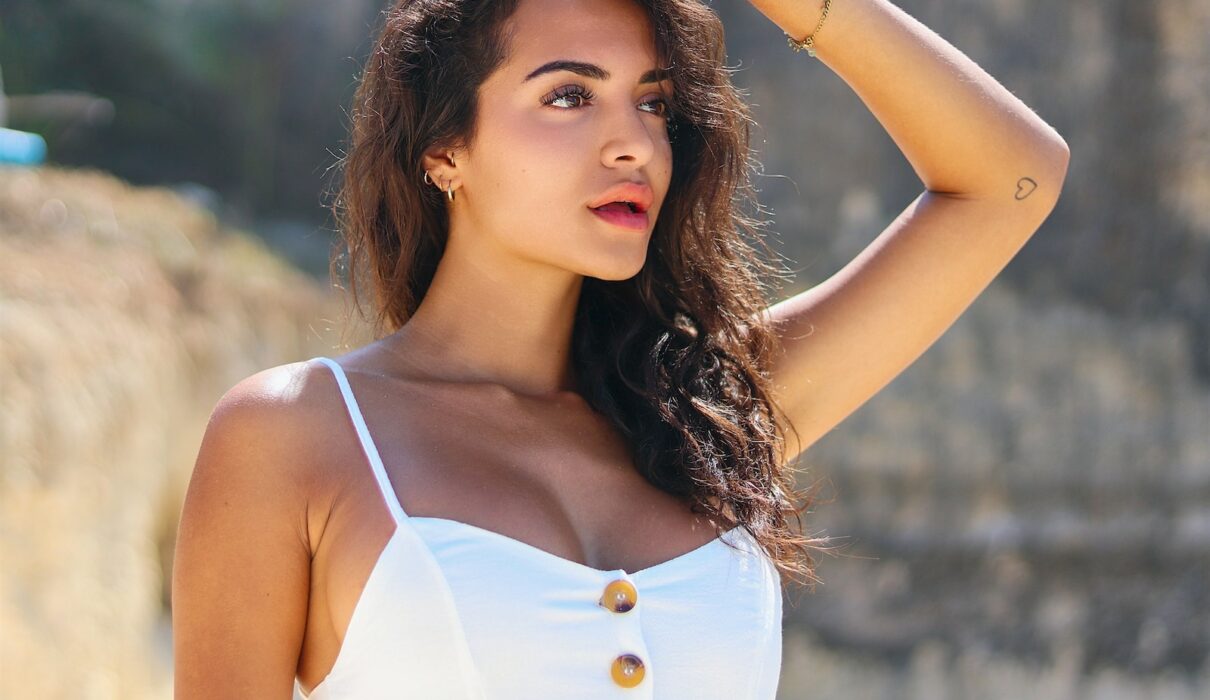 vrouw in wit tanktopje houdt haar haar vast