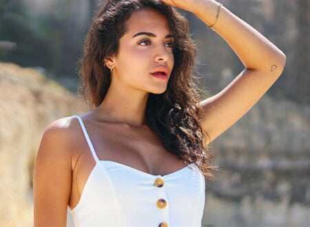 vrouw in wit tanktopje houdt haar haar vast