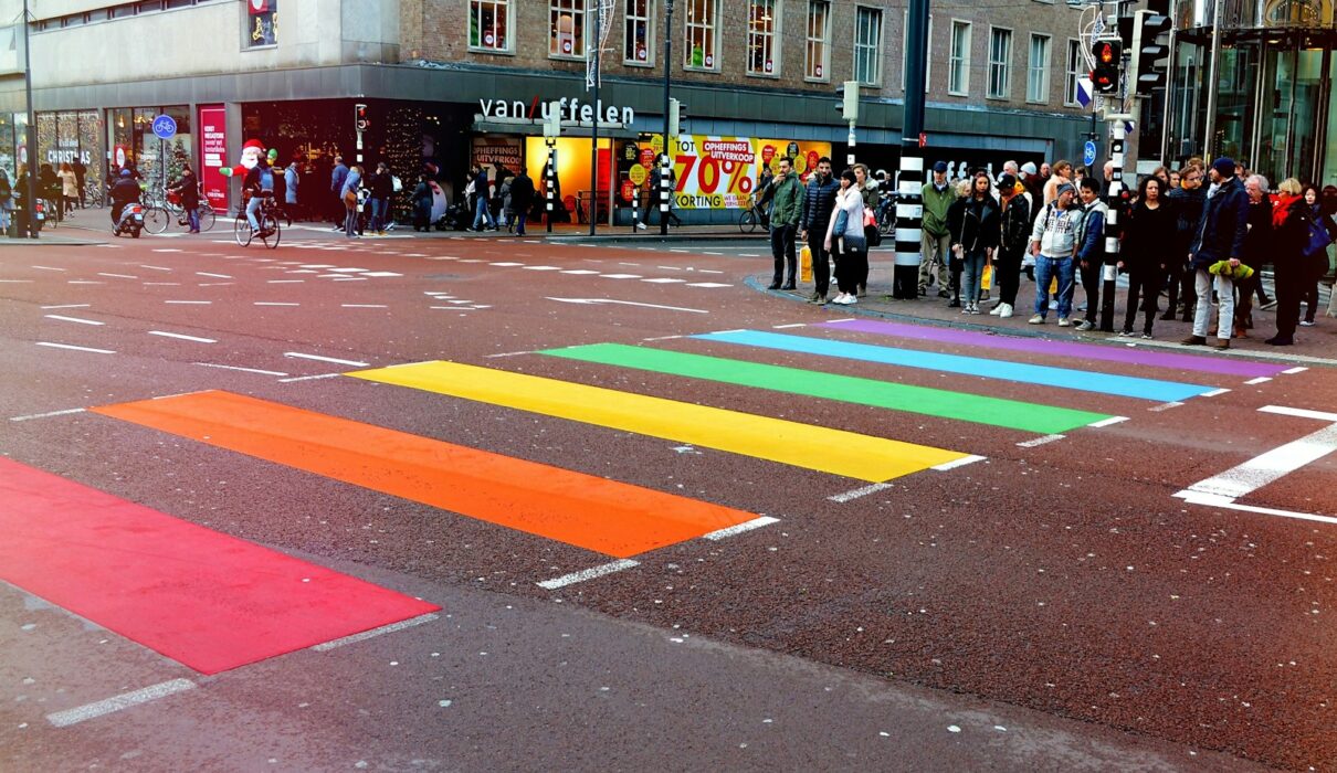 Personas paradas en la calle frente a una línea peatonal multicolor