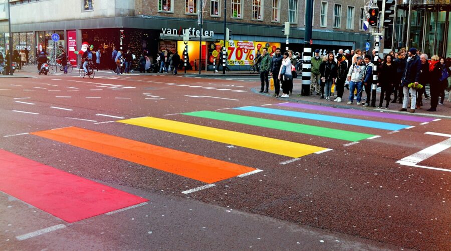 Personas paradas en la calle frente a una línea peatonal multicolor